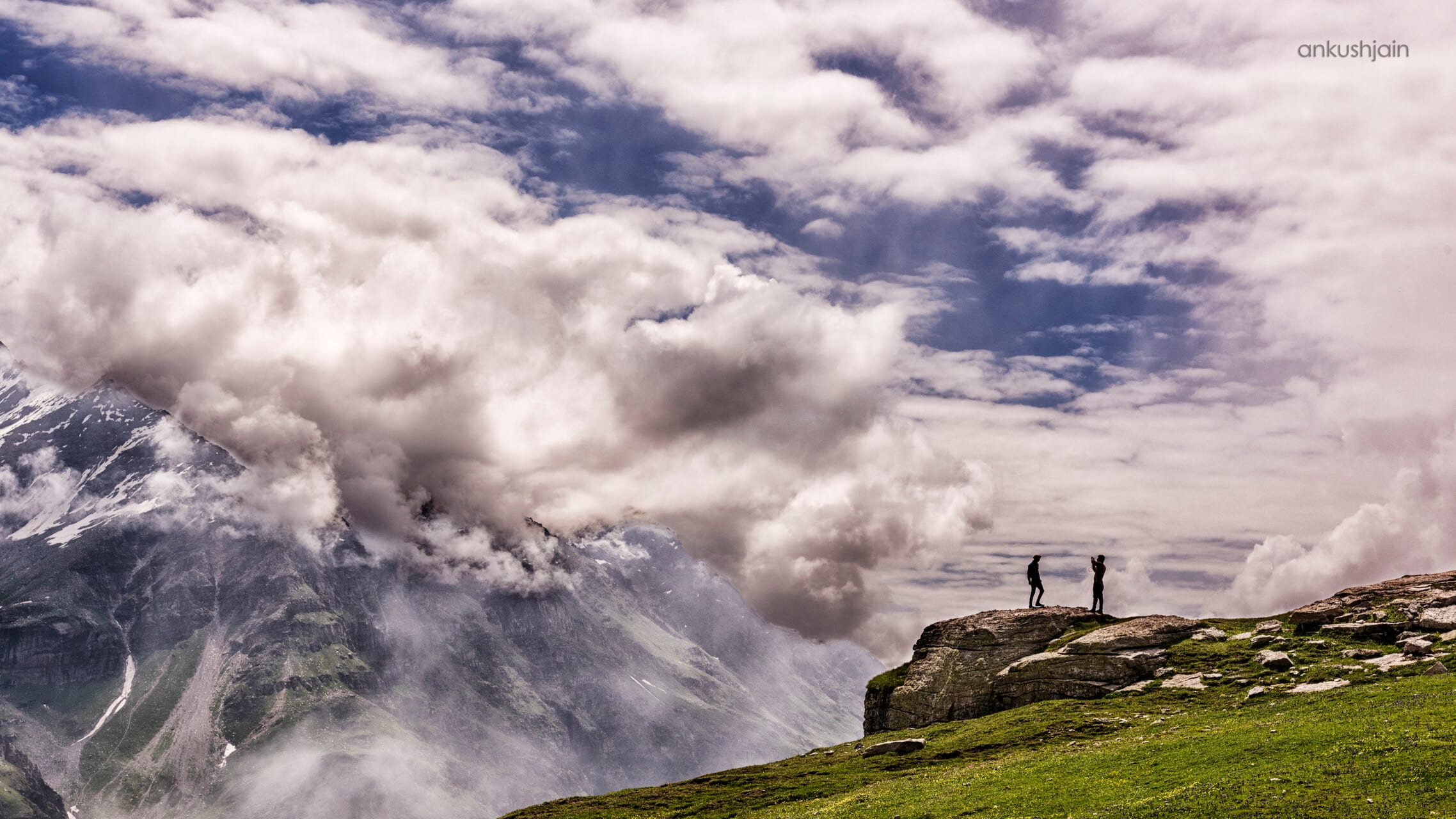 A mountain ridge wreathed in low clouds, peaks emerging through the mist