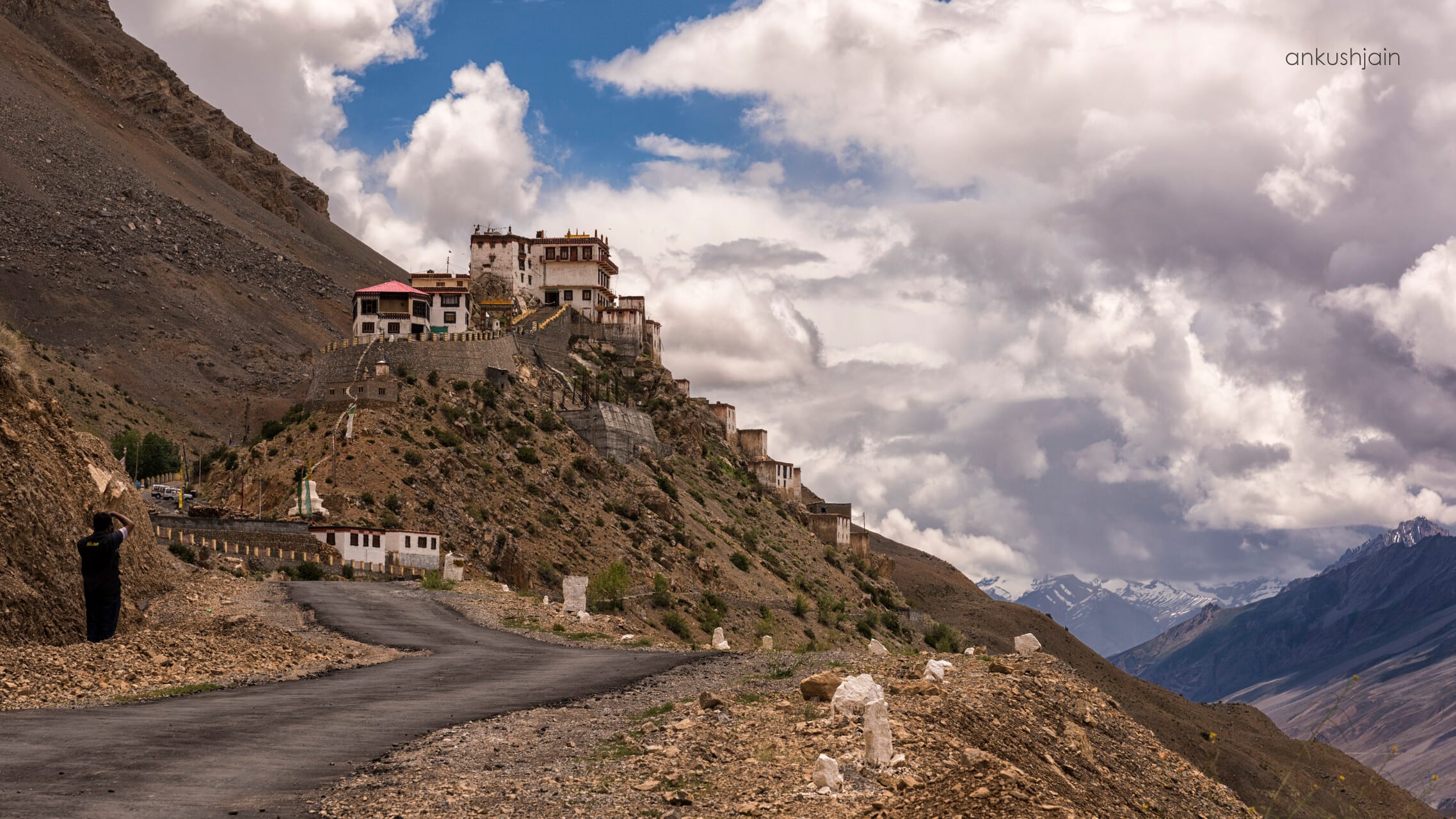 A whitewashed Buddhist monastery perched on a ridge above the valley
